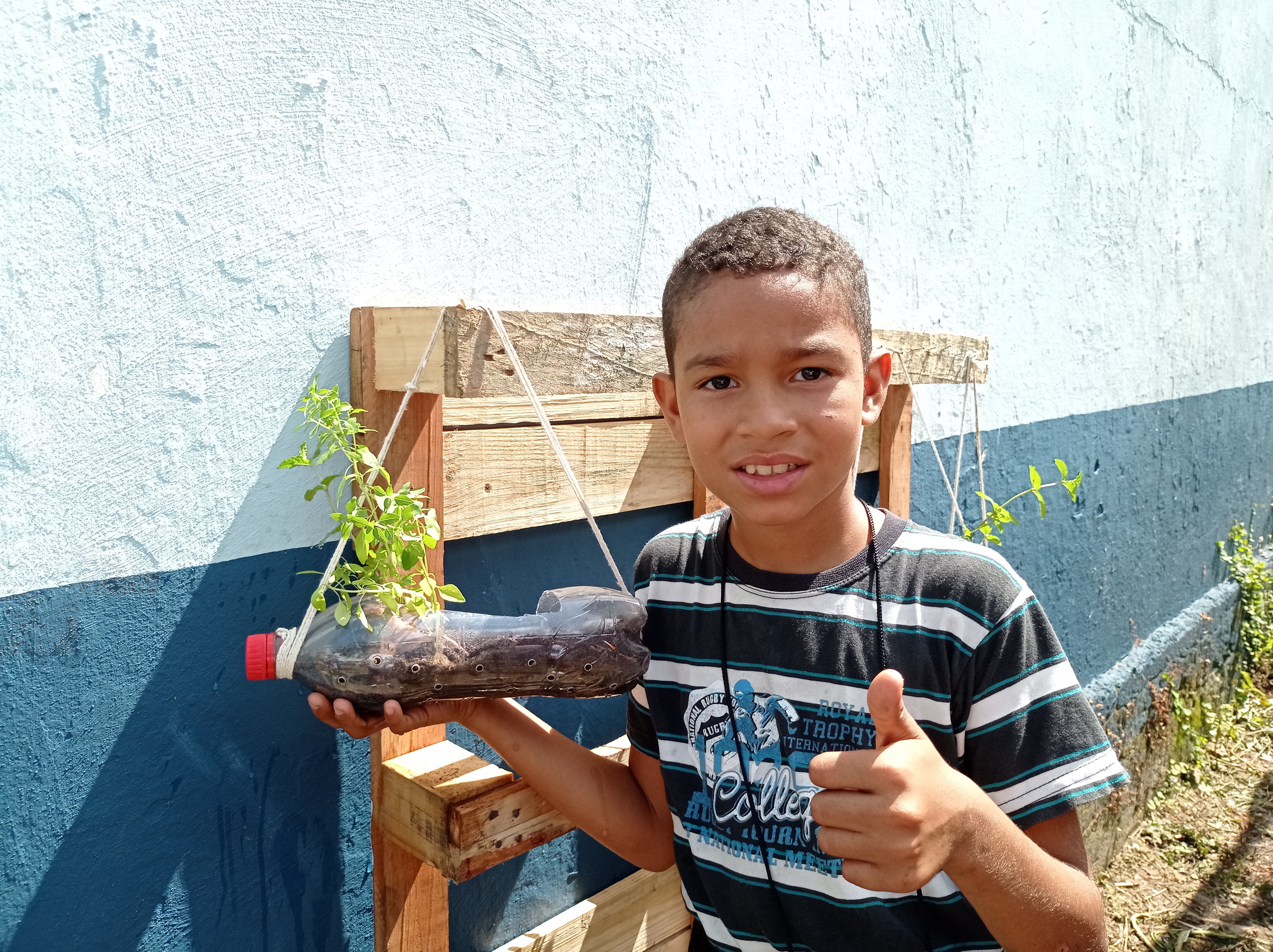 Crianças põem a mão na terra e aprendem a plantar hortaliças e flores em escola municipal