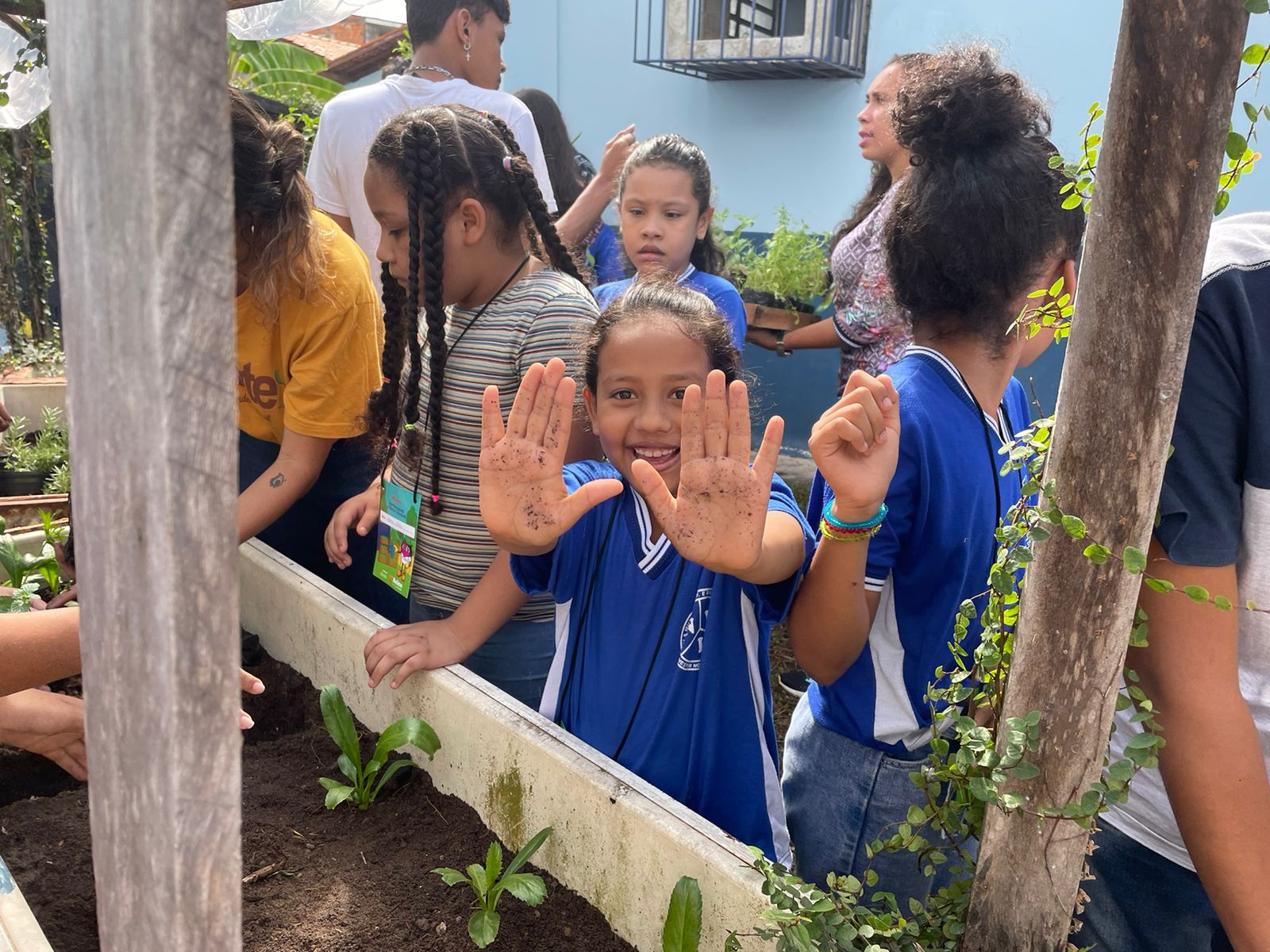 Crianças põem a mão na terra e aprendem a plantar hortaliças e flores em escola municipal